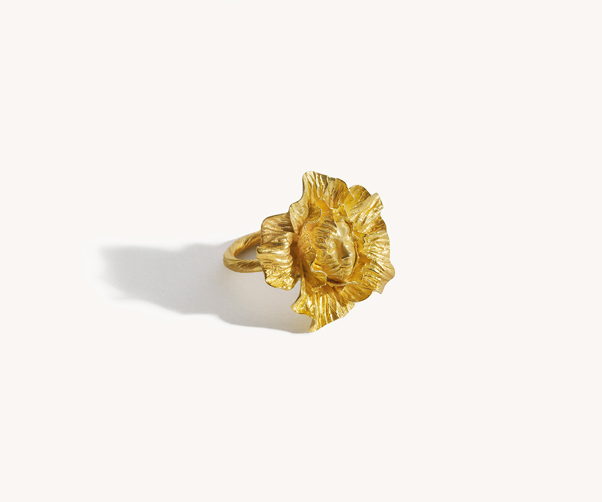 An 18K yellow gold ring shaped like a face hidden among leaves.