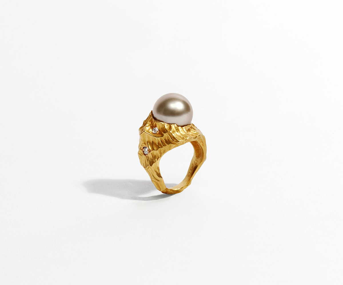 A solid 18K yellow gold ring shaped like waves in the water, with a large round black pearl set at the center.