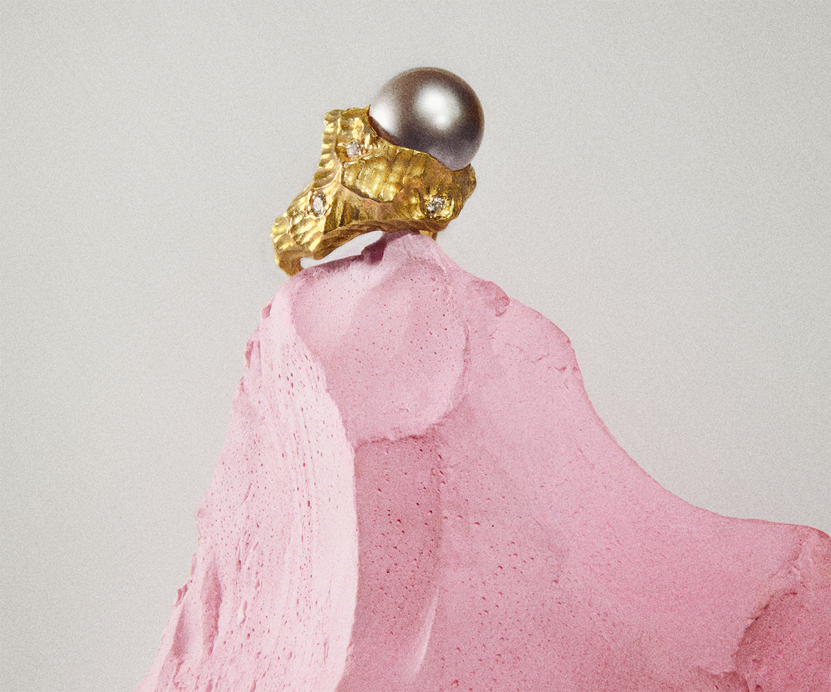A solid 18K yellow gold ring shaped like waves in the water, with a large round black pearl set at the center.