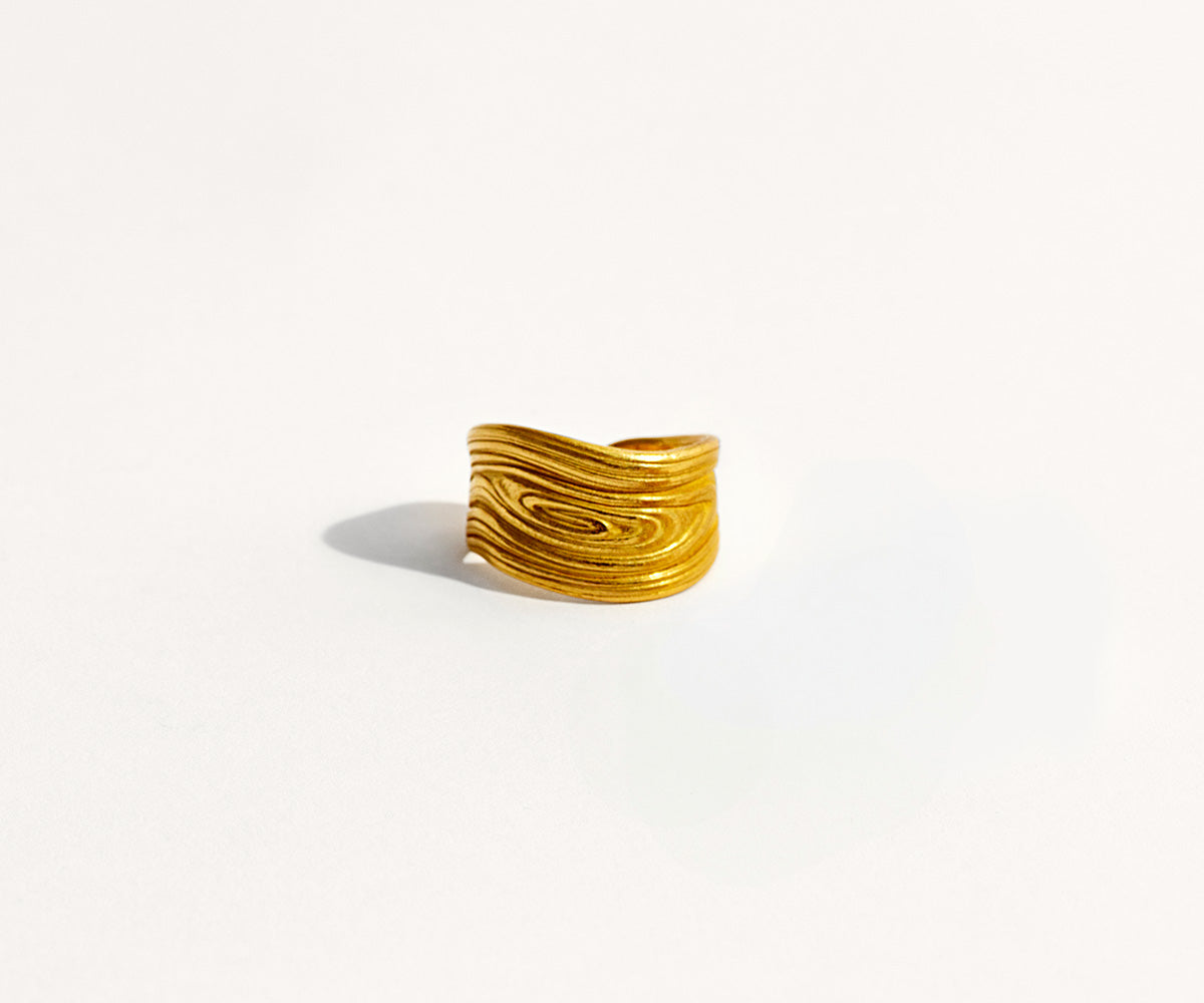 An 18K yellow gold ring with a texture resembling tree bark.