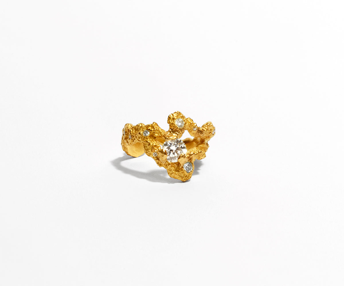 An 18K yellow gold ring with 13 small diamonds, shaped organically with a big stone centred in the middle.