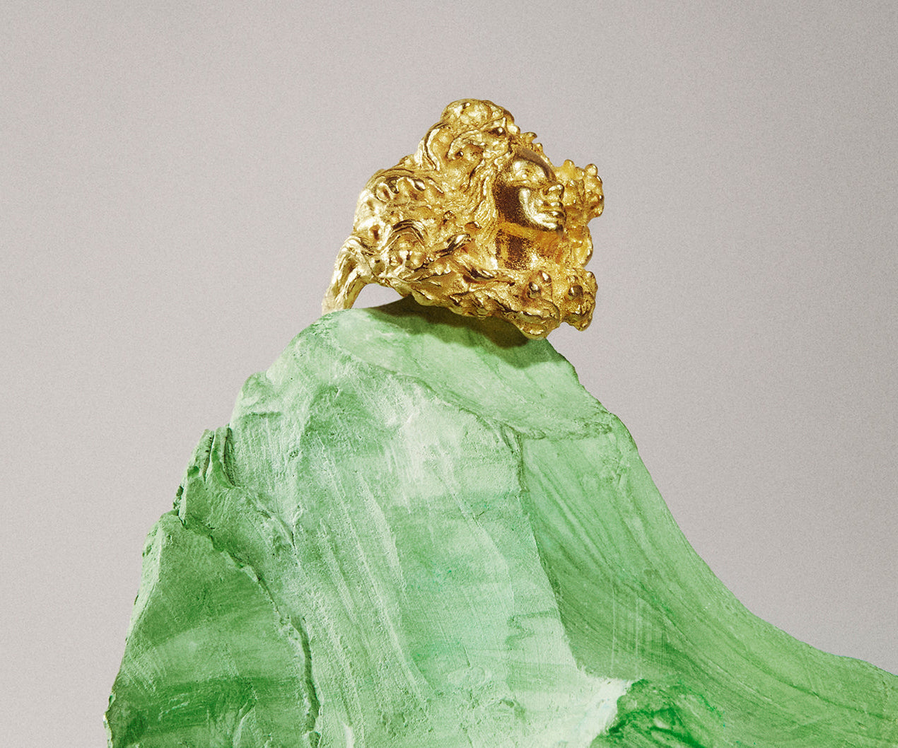 An 18K yellow gold ring shaped like a woman, emerging from between the branches of an oak tree.