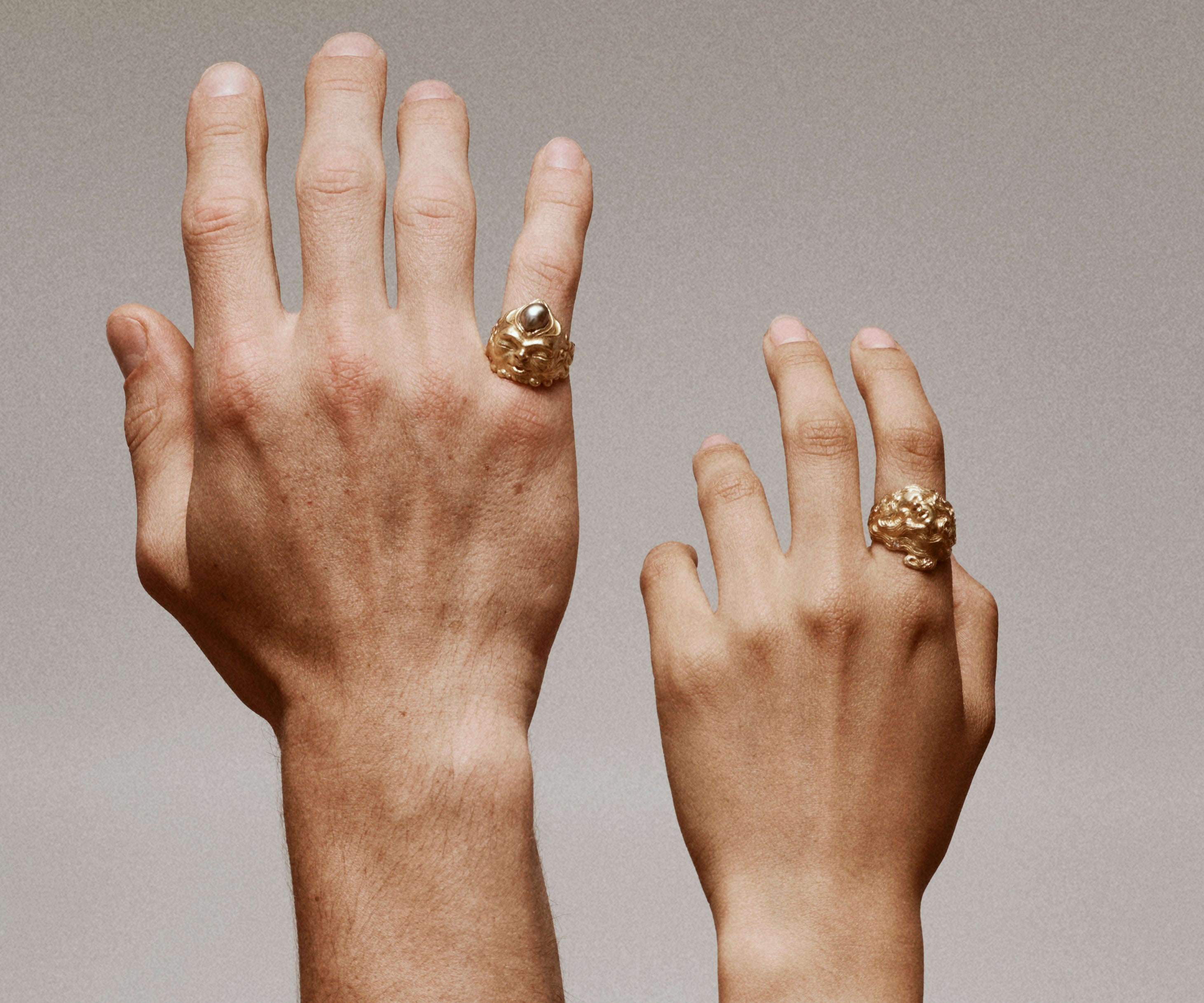 Two hands wearing rings in 18K yellow gold. The rings ensembles faces.