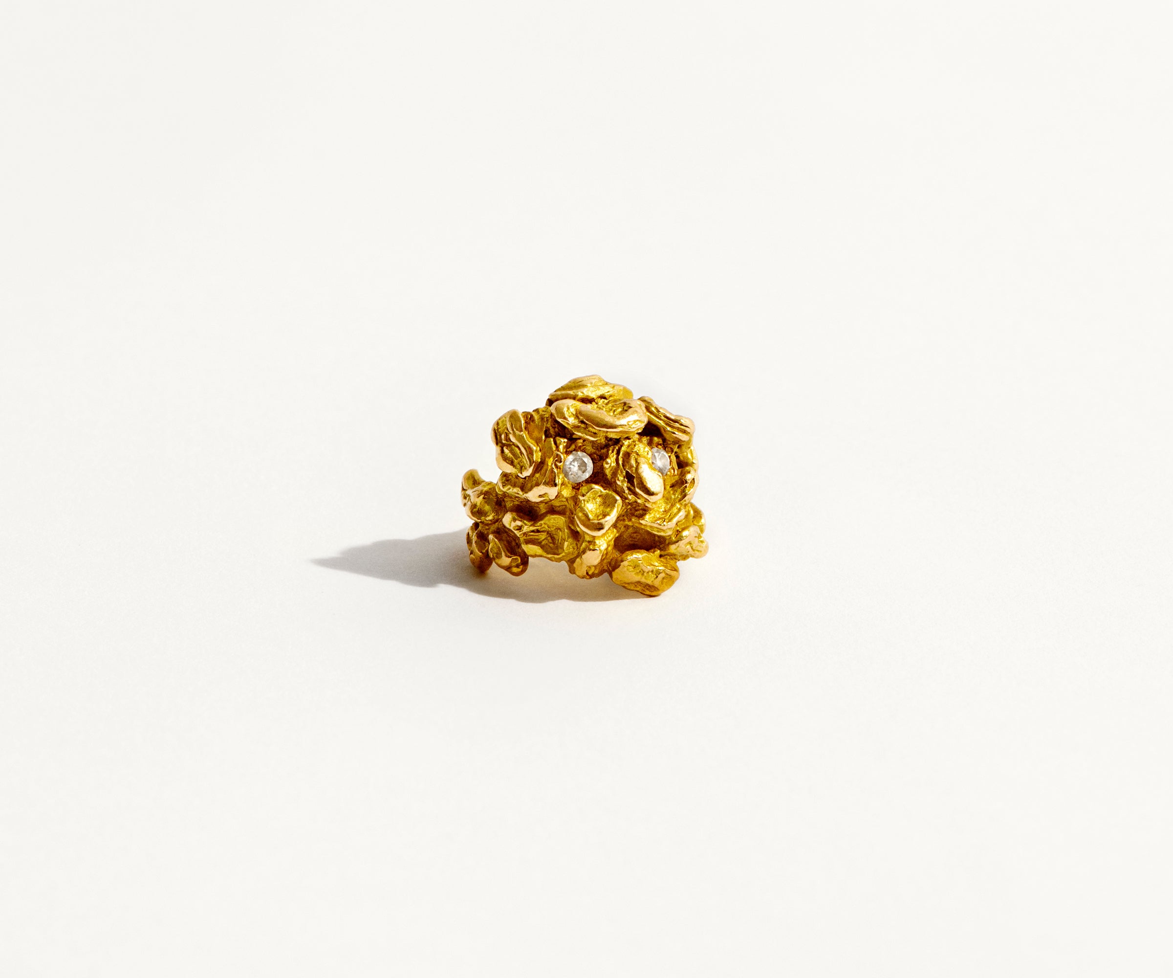 An 18K yellow gold ring shaped like a man, emerging from between the bark.