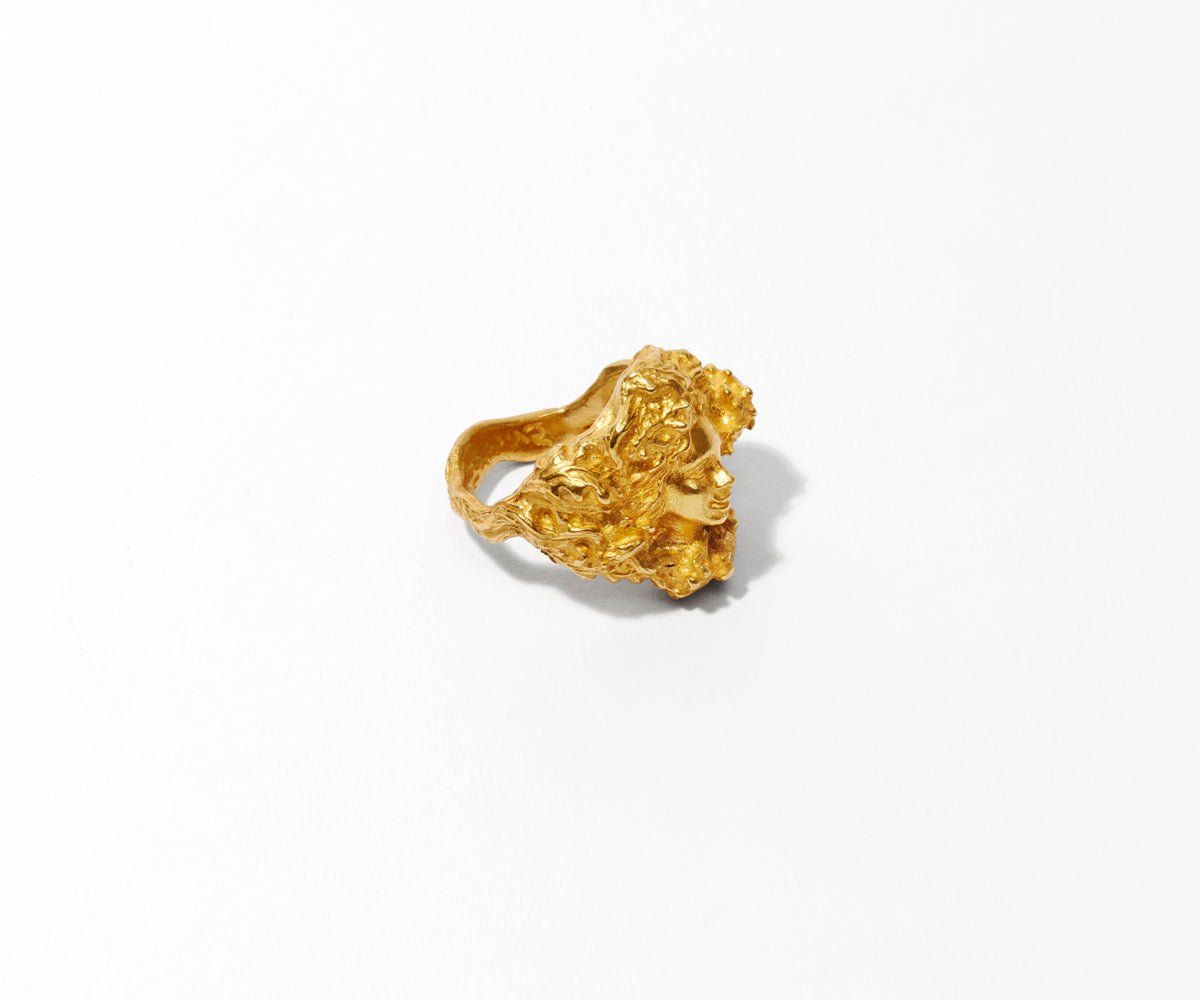 An 18K yellow gold ring shaped like a woman, emerging from between the branches of an oak tree.