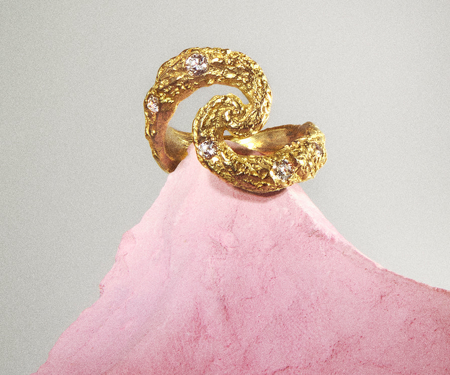 An 18K yellow gold ring, set with 5 diamonds, designed to resemble gold shaped by meteorite or asteroid showers, with craters across its surface, and set  Shaped almost like an 'S,' it draws inspiration from the universe.