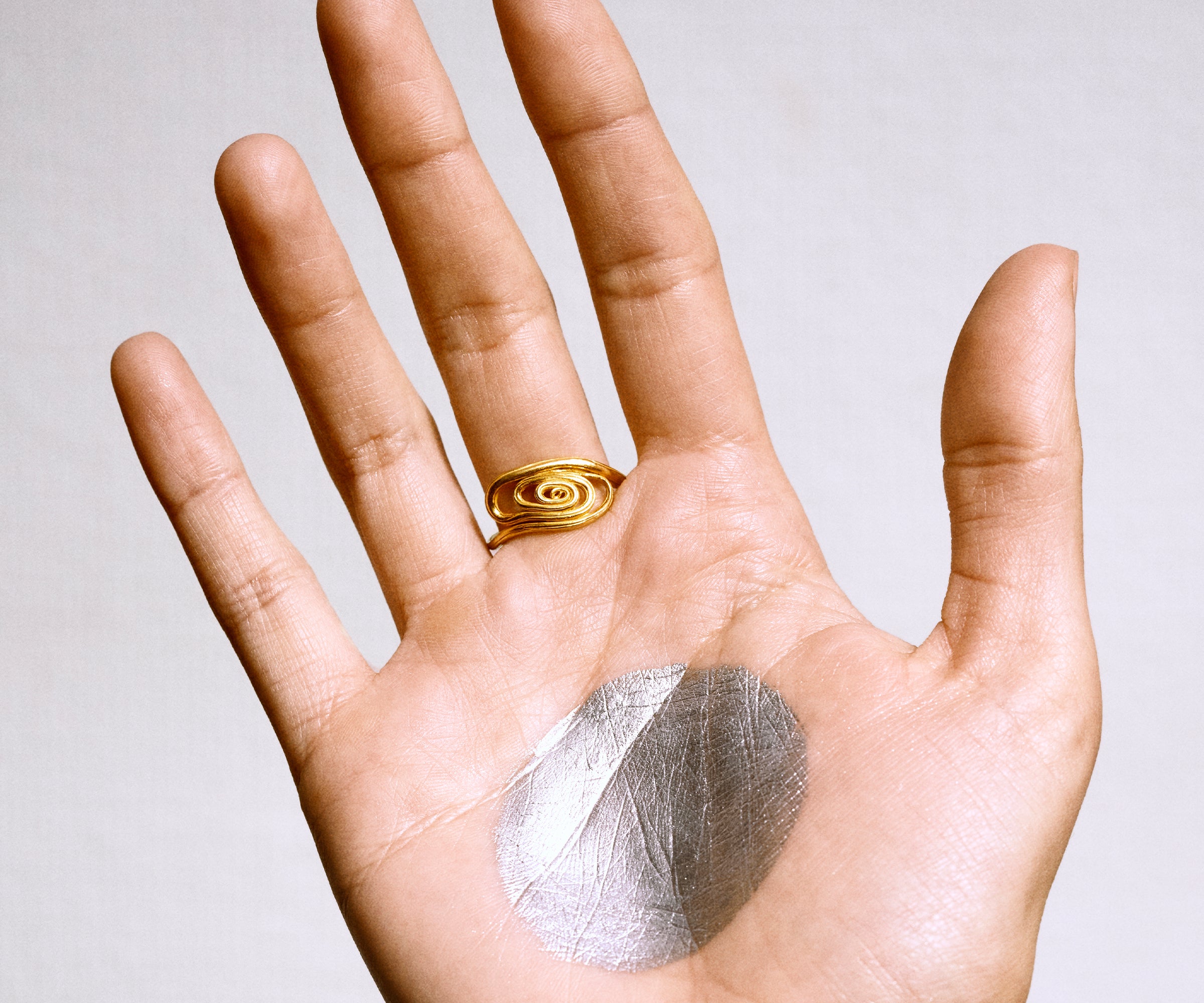 An elegant 18K yellow gold ring designed to resemble the delicate shape of a small fan, with soft, sweeping curves that create a sense of movement and grace.
