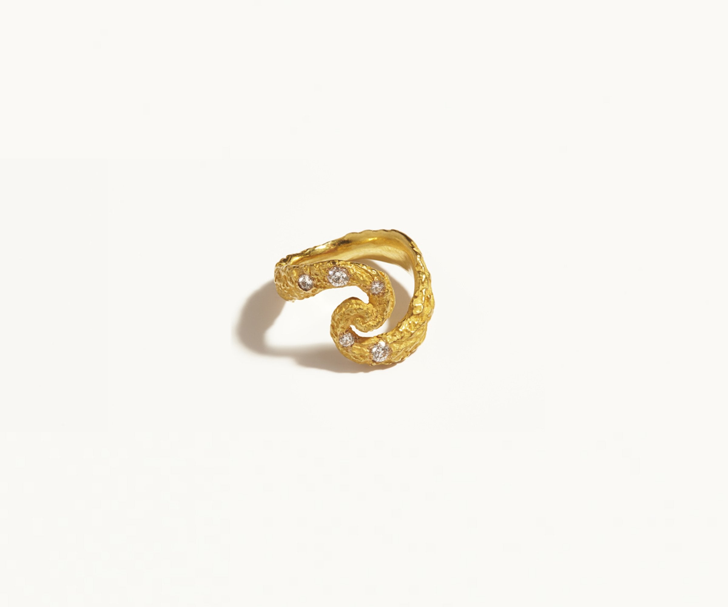 An 18K yellow gold ring, set with 5 diamonds, designed to resemble gold shaped by meteorite or asteroid showers, with craters across its surface, and set  Shaped almost like an 'S,' it draws inspiration from the universe.