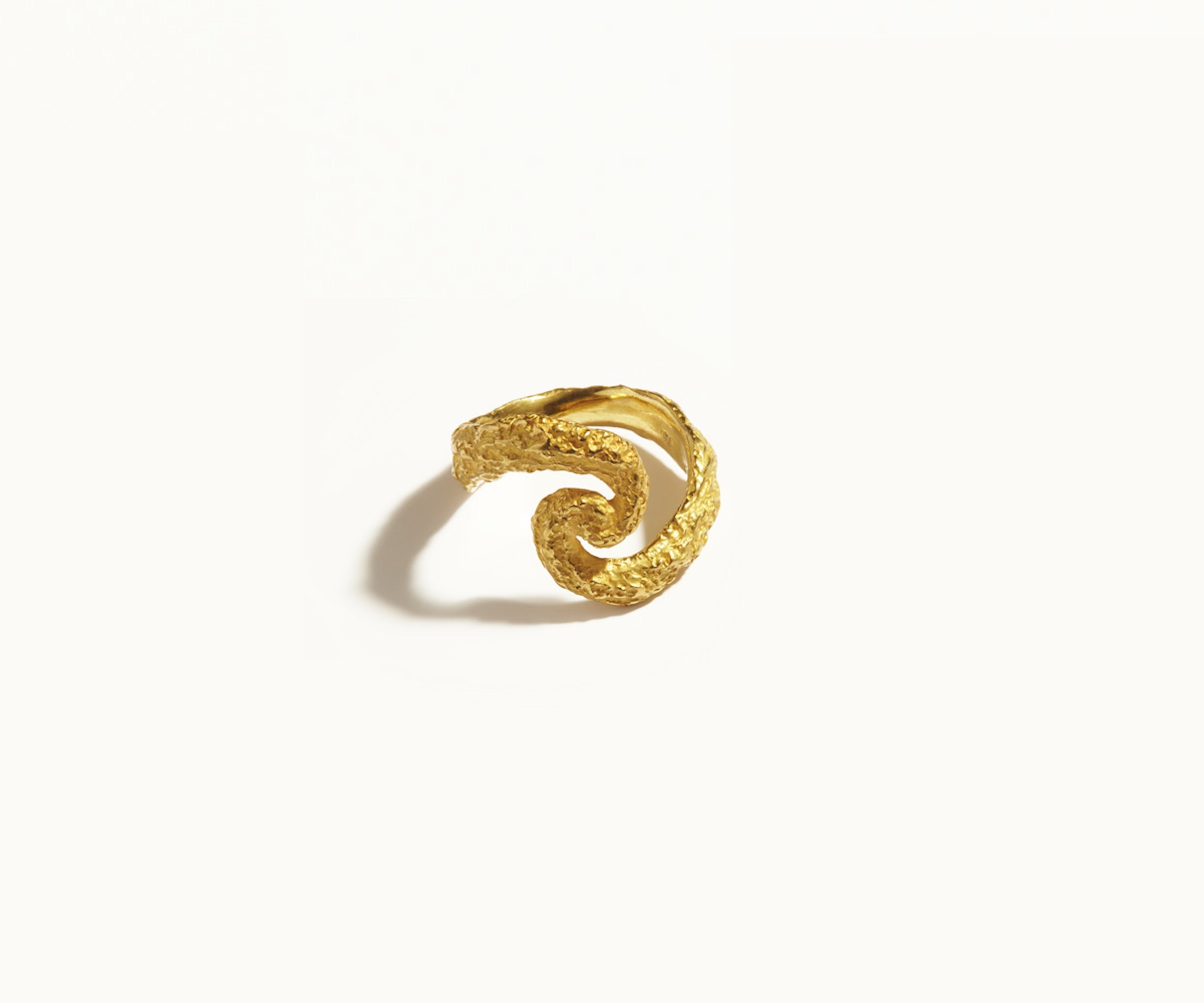 An 18K yellow gold ring, designed to resemble gold shaped by meteorite or asteroid showers, with craters across its surface. Shaped almost like an 'S,' it draws inspiration from the universe.