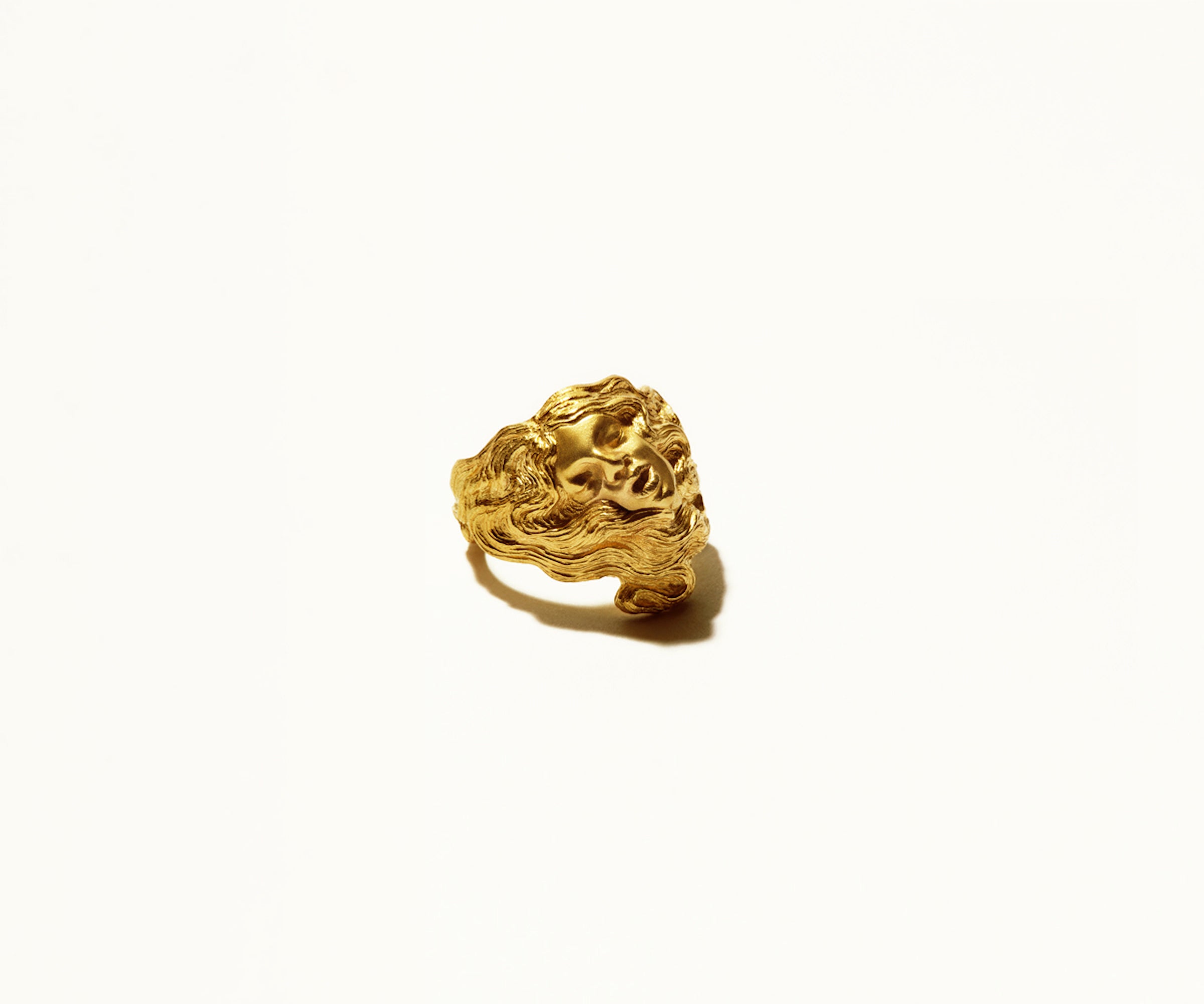 An 18K yellow gold ring, organically shaped to resemble a woman, with her hair seamlessly integrated into the design.