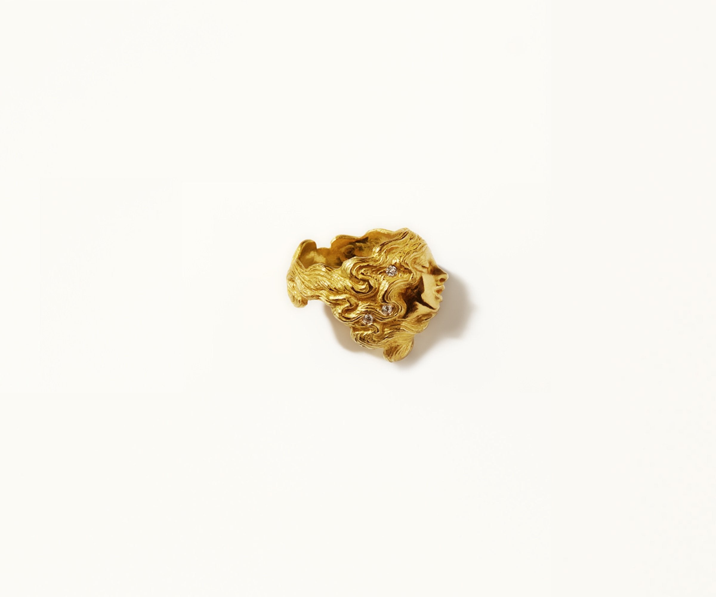 An 18K yellow gold ring with small diamonds, organically shaped to resemble a woman, with her hair seamlessly integrated into the design.