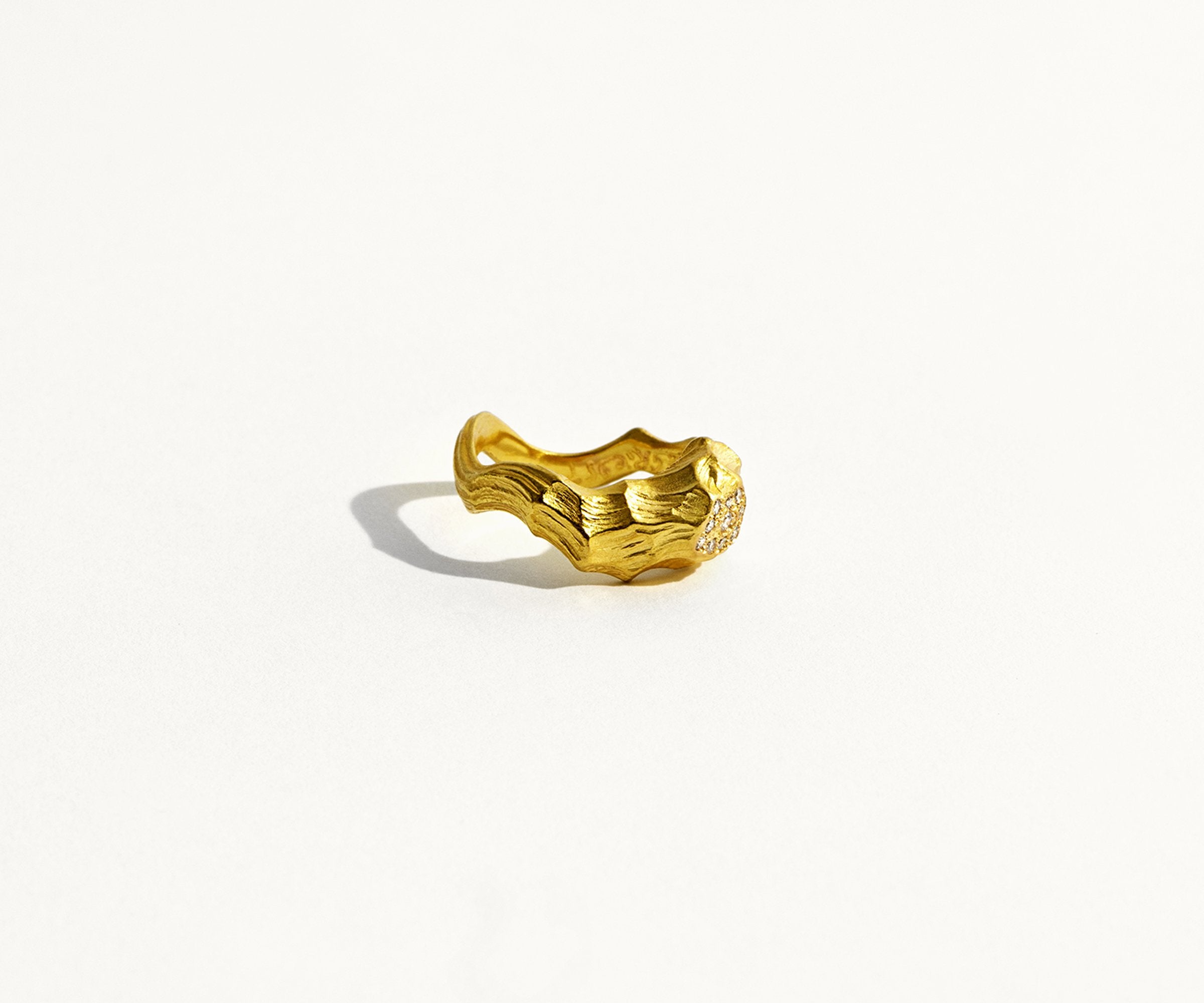 An 18K yellow gold ring shaped like waves in water, with 10 small diamonds set along the front.