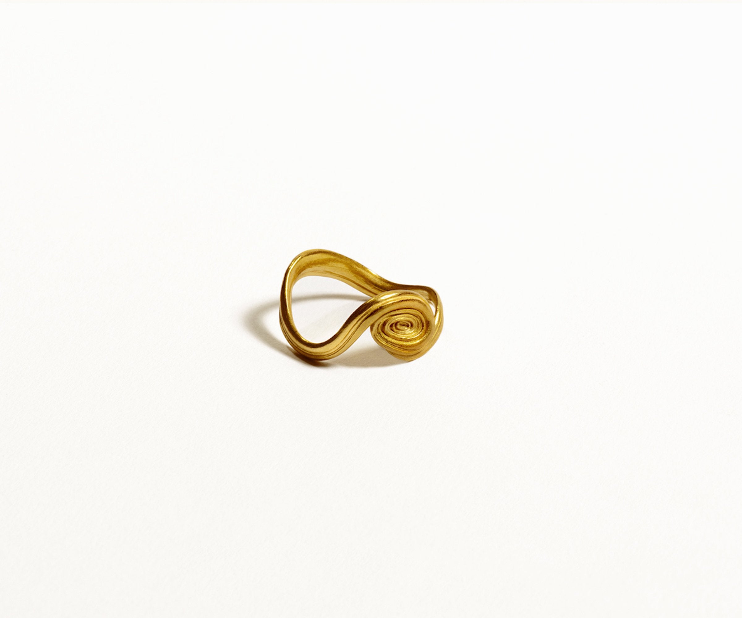 An 18K yellow gold ring with a spiral design, showcasing an organic shape, against a white background.