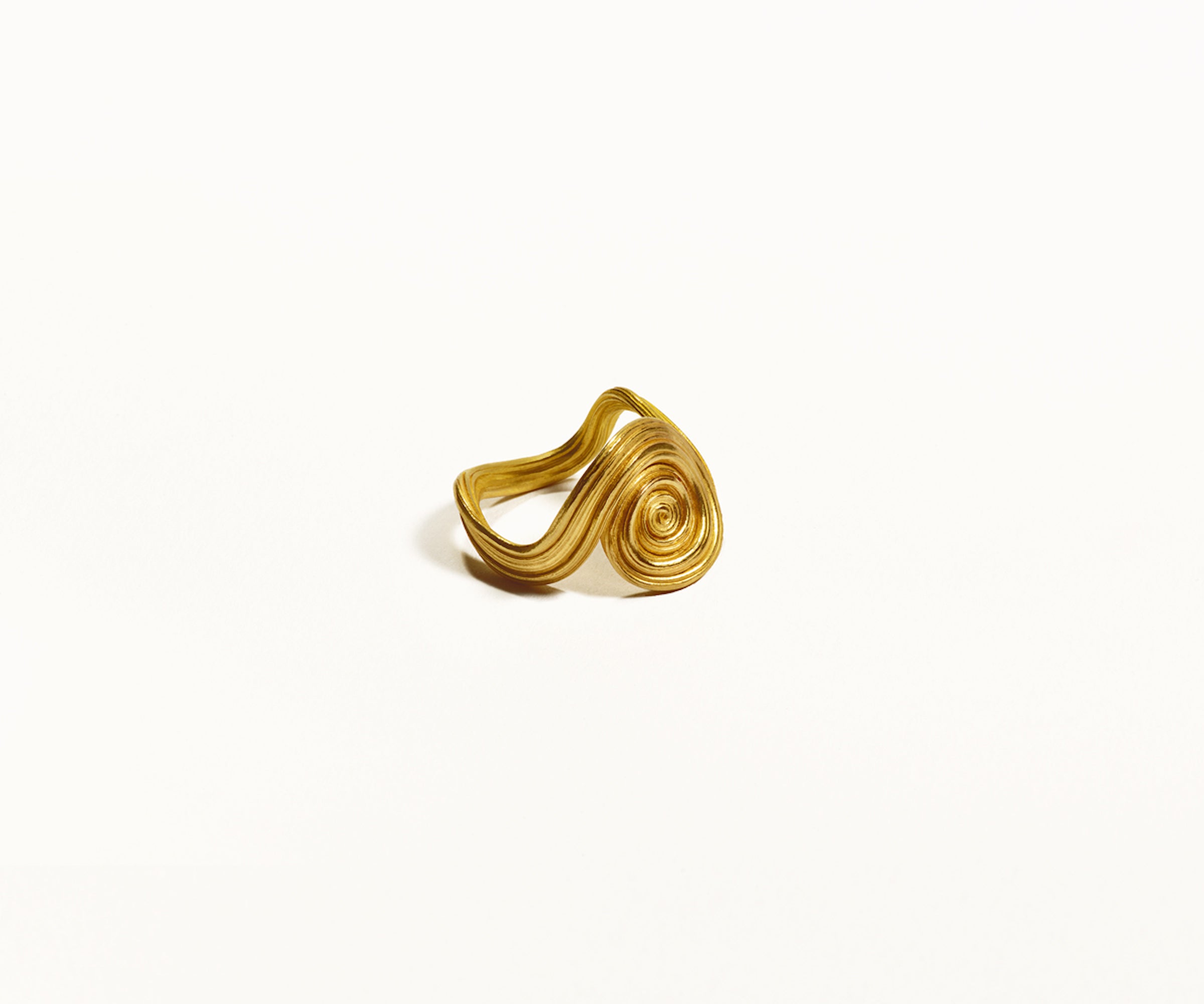 A spiral-shaped ring made of 18K yellow gold, featuring an organic design, set against a clean white background.