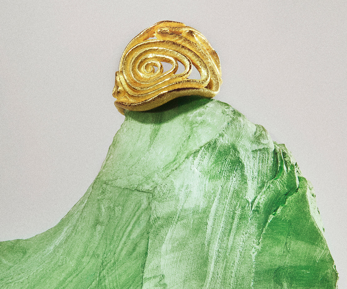 An 18K yellow gold ring shaped organically, inspired by nature. The center part resembles a spiral.